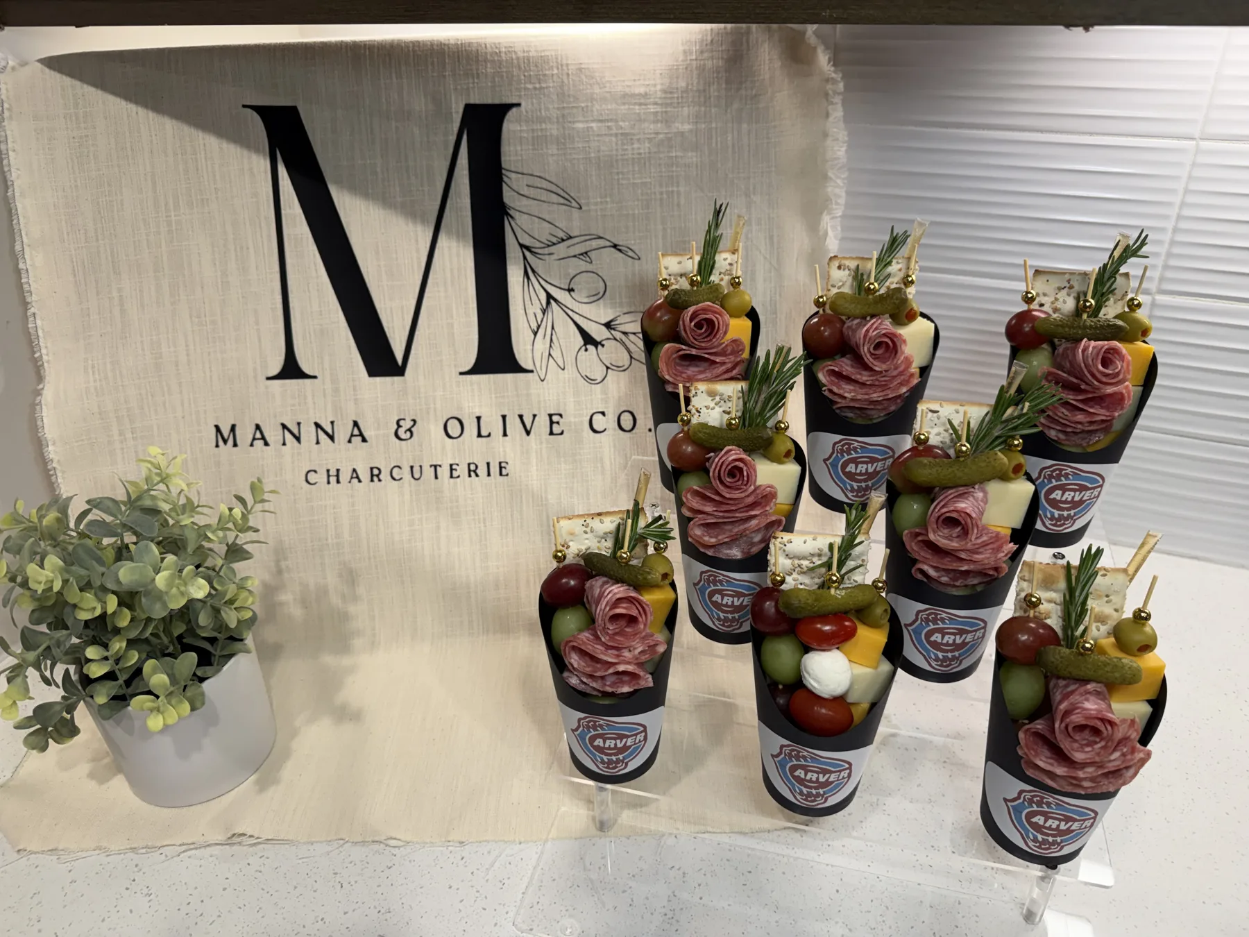 Charcuterie cups with custom event labels on a tiered stand